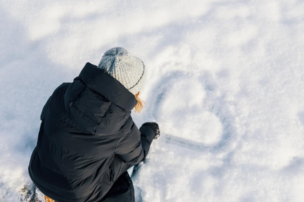 Opiskelija piirtää sydämen lumeen