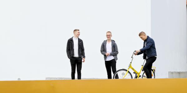 Kolme opiskelijaa kampuksella.