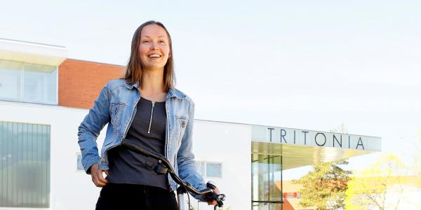 Tyttö hymyilee polkupyörän vierellä