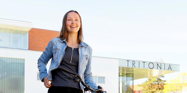 Tyttö hymyilee polkupyörän vierellä