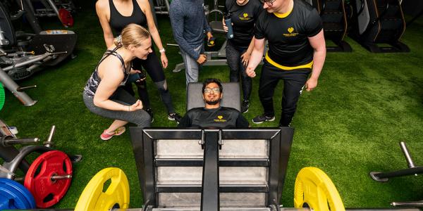 Athlete doing leg press and friends cheering them on