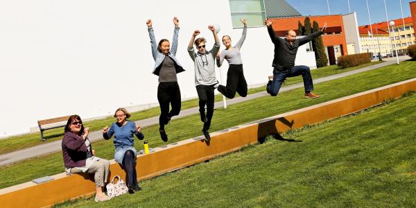Iloiset opiskelijat hyppäävät penkiltä alas