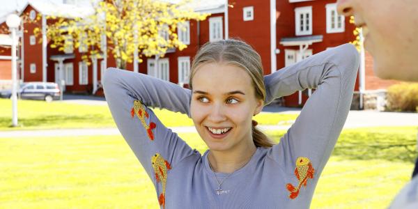 Tyttö hymyilee kädet ylös nostettuina