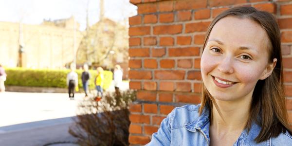 Tyttö hymyilee Konttori-rakennuksen vierellä