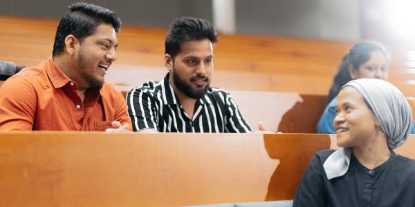 Three students discussing and smiling.