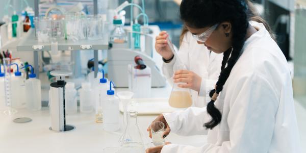 Kaksi nuorta tyttöä tekemässä töitä kemian labroratoriossa