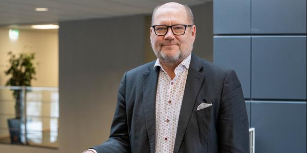 Juha Gröhn nojaa kaiteeseen ja hymyilee kameralle