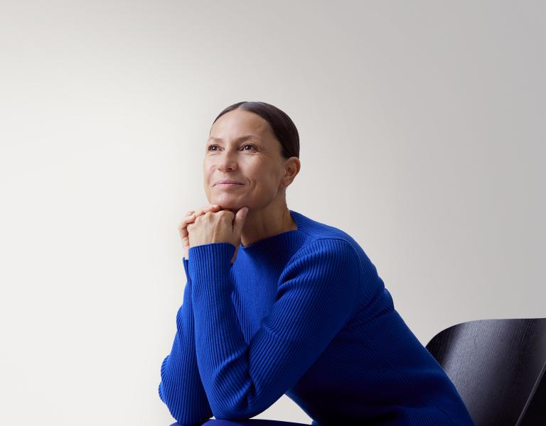 Opin.fi-palvelu. Nainen sinisessä paidassa nojaa pöytään ja katsoo kaukaisuuteen.