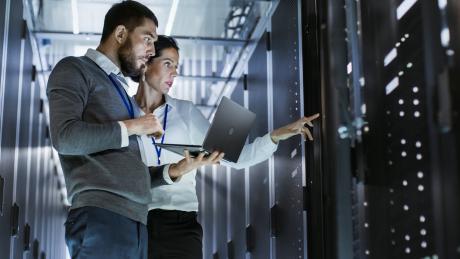 Two IT specialists looking at a server cabinet together