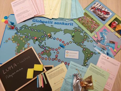Globaalit sankarit lautapelin materiaalit: pelilauta ja nappulat, palapelit, tehtäväkortit ja liitutaulut